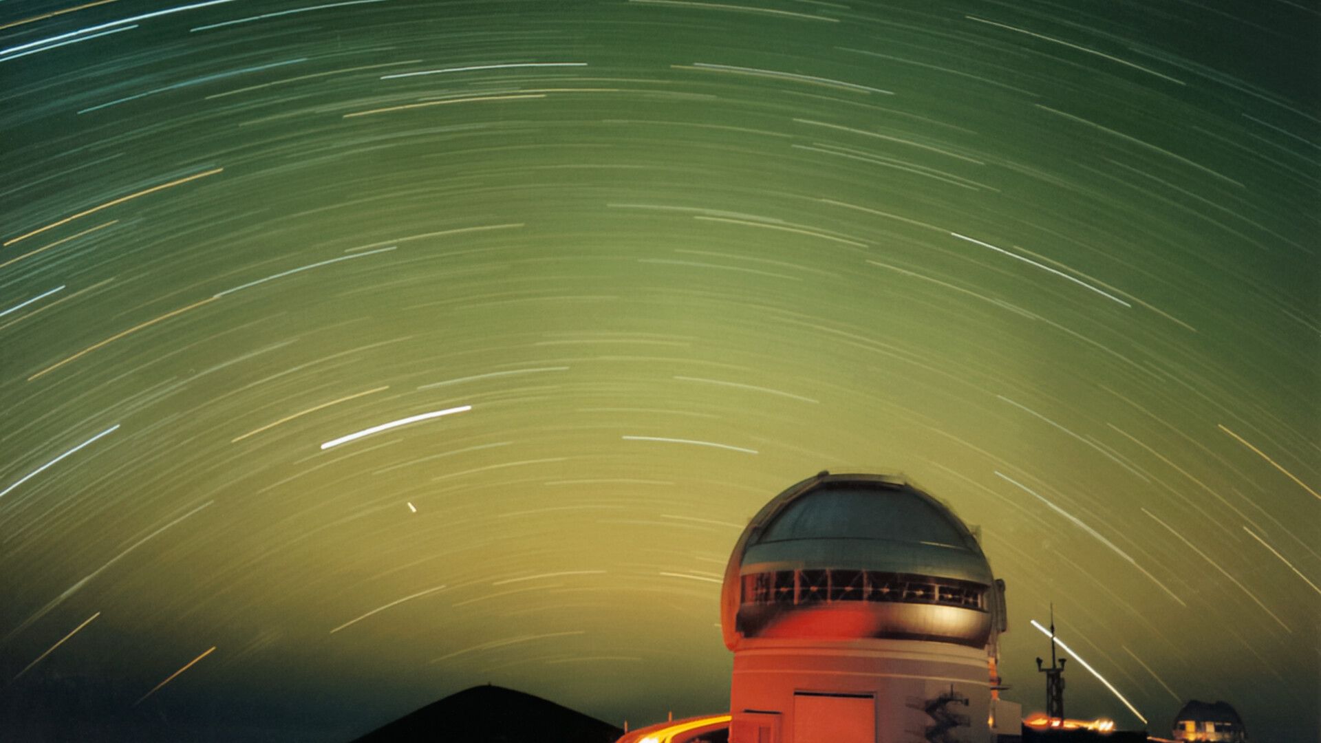 Listras de estrelas e satélites em uma foto verde do céu noturno do dia 12 de novembro de 2025